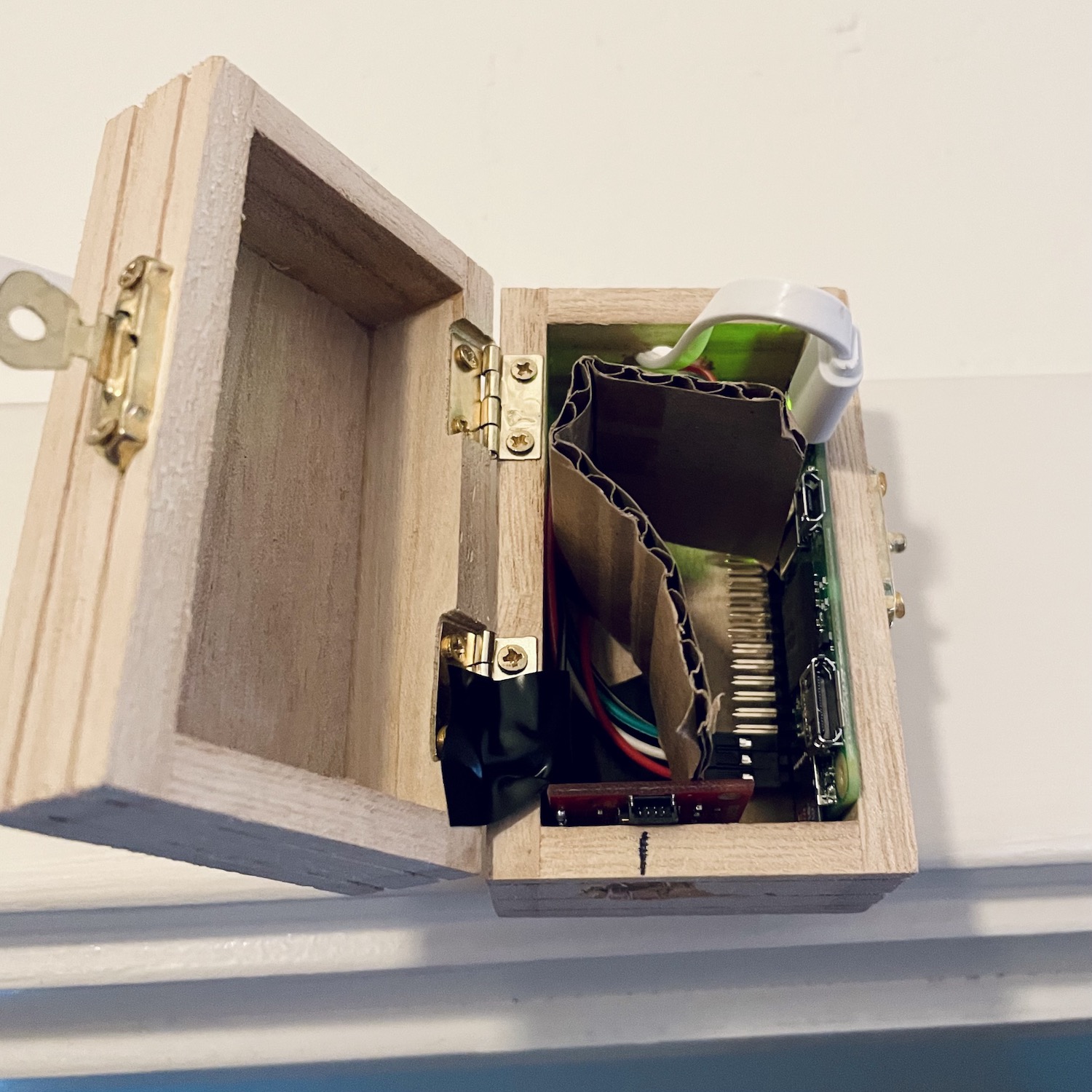 A Raspberry Pi Zero and AMG8833 thermopile sensor shoved in a small wooden box, and taped to the top of a door